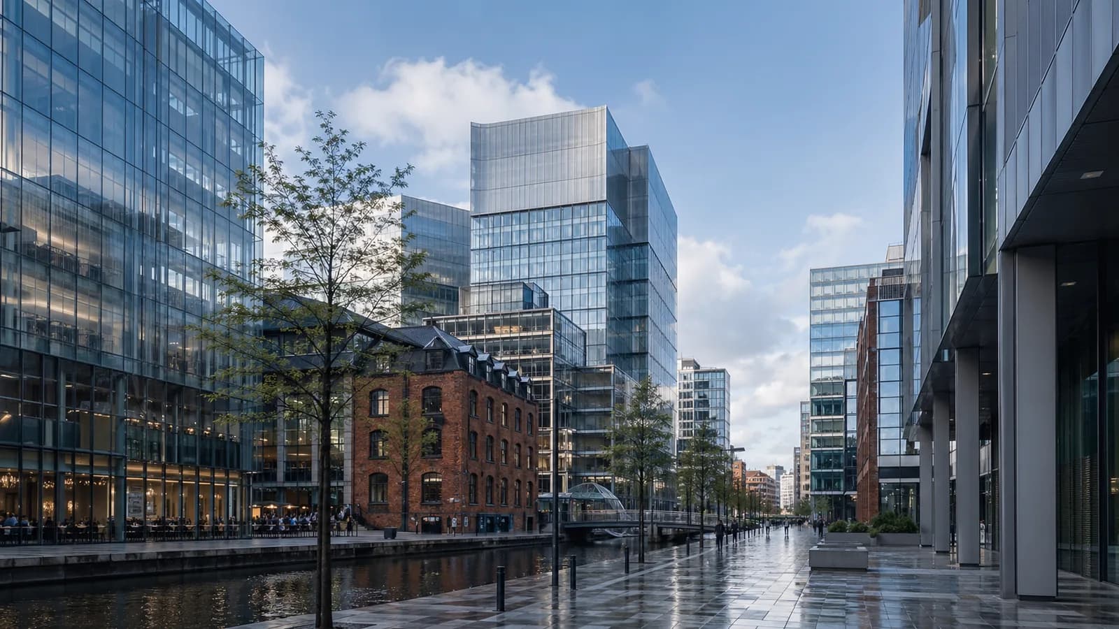 Modern glass office towers in Manchester city centre on a bright weekday afternoon.